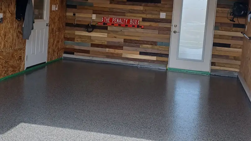 Clean garage interior with smooth, speckled gray floor and wooden accent wall.